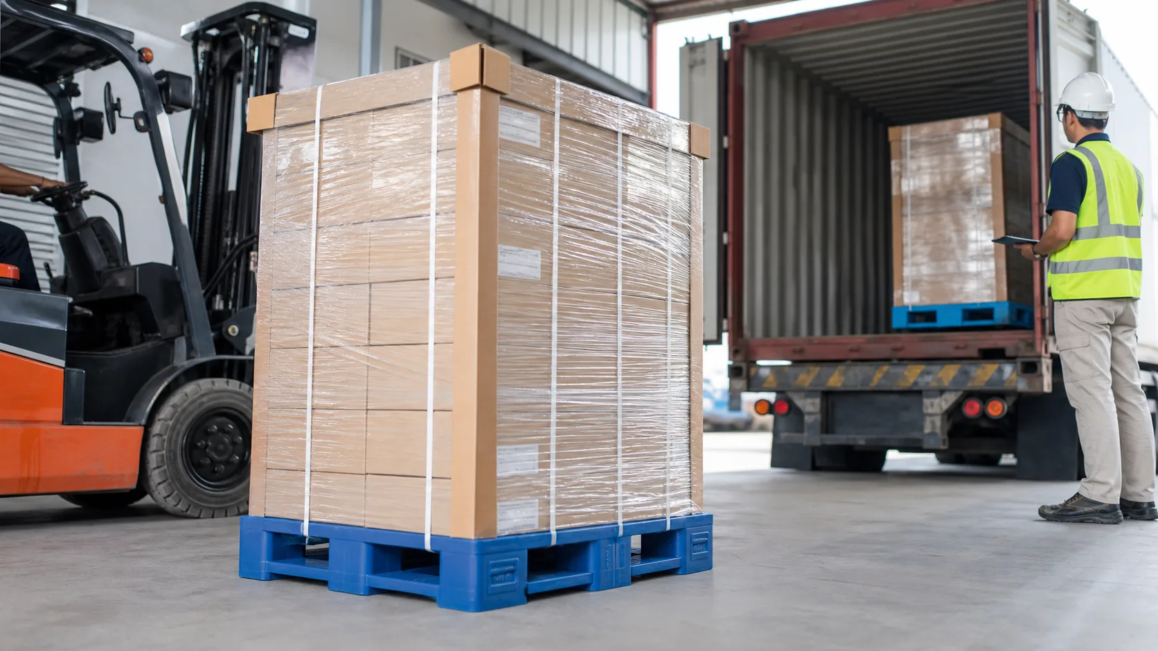 Wrapped cartons on blue plastic pallets being checked for load stability at a warehouse loading dock
